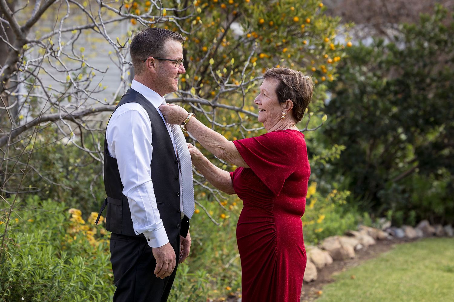 A Mother helping her son with his tie during his wedding preparations in the gardens at Buller Wines in Rutherglen
