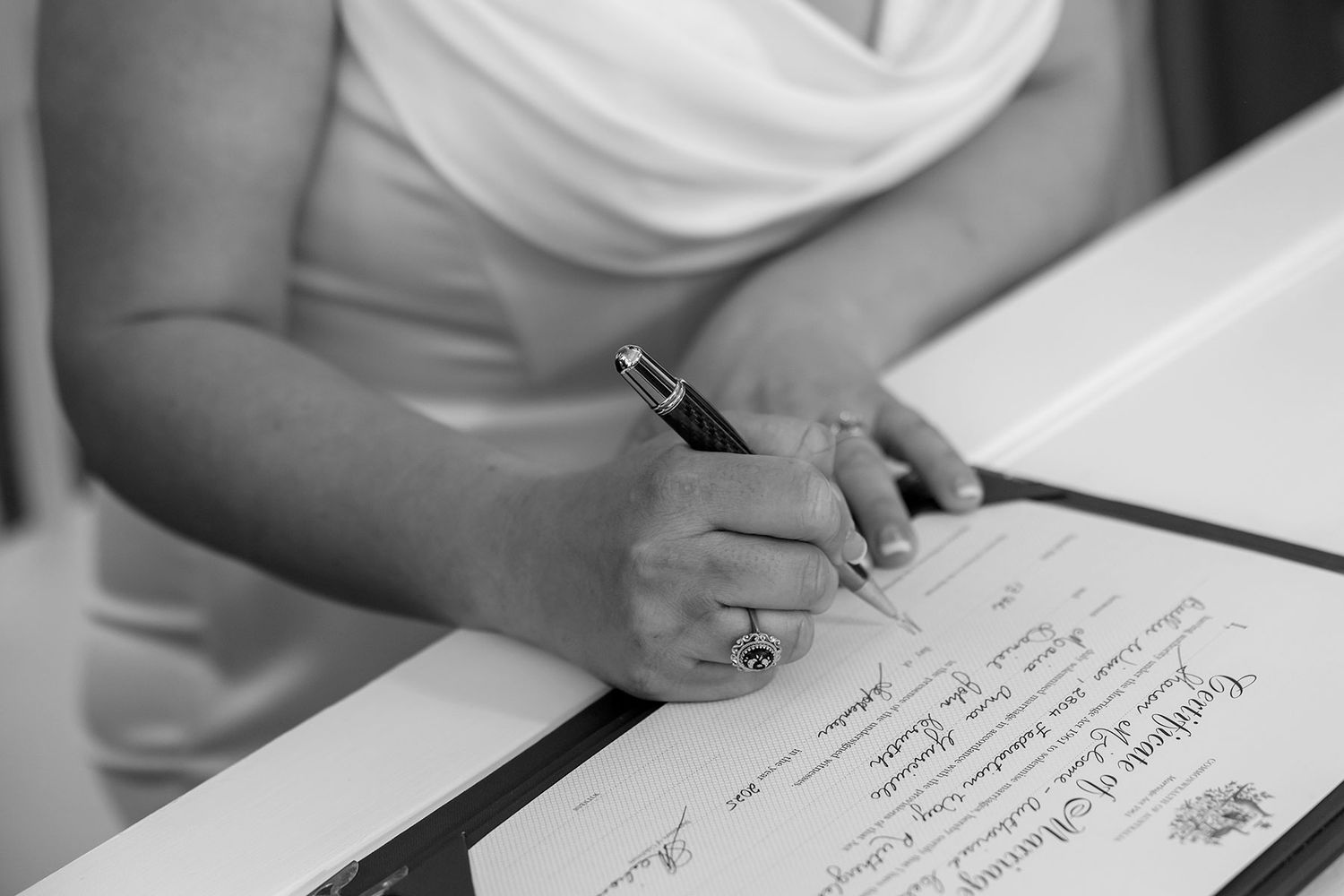 A close up image of a Brides hands signing the Register after her outdoor wedding ceremony at Buller Wines.