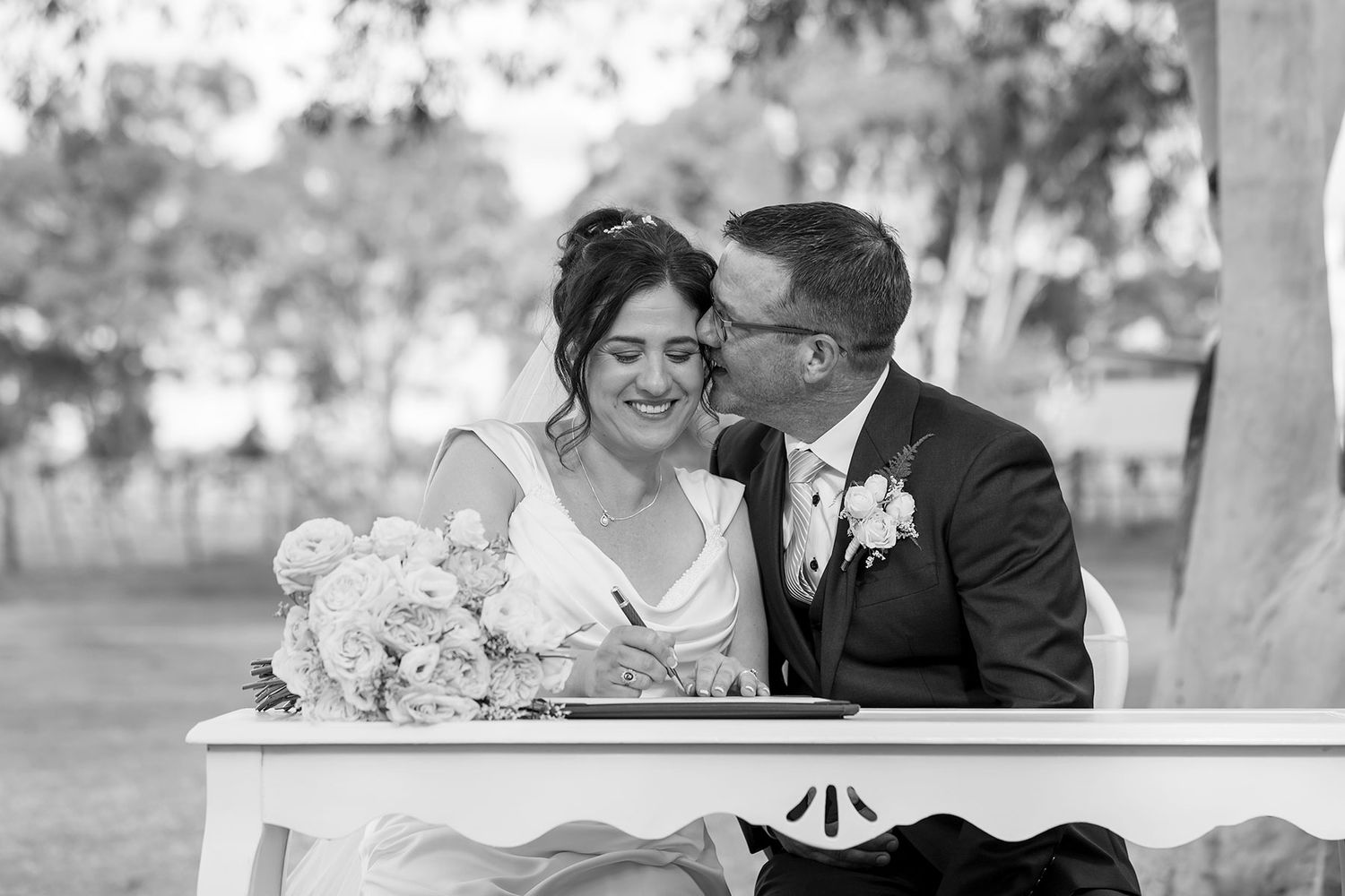 Black + White wedding photo of a Bride and Groom sharing a moment while signing the wedding register in an outdoor ceremony at Buller Wines.