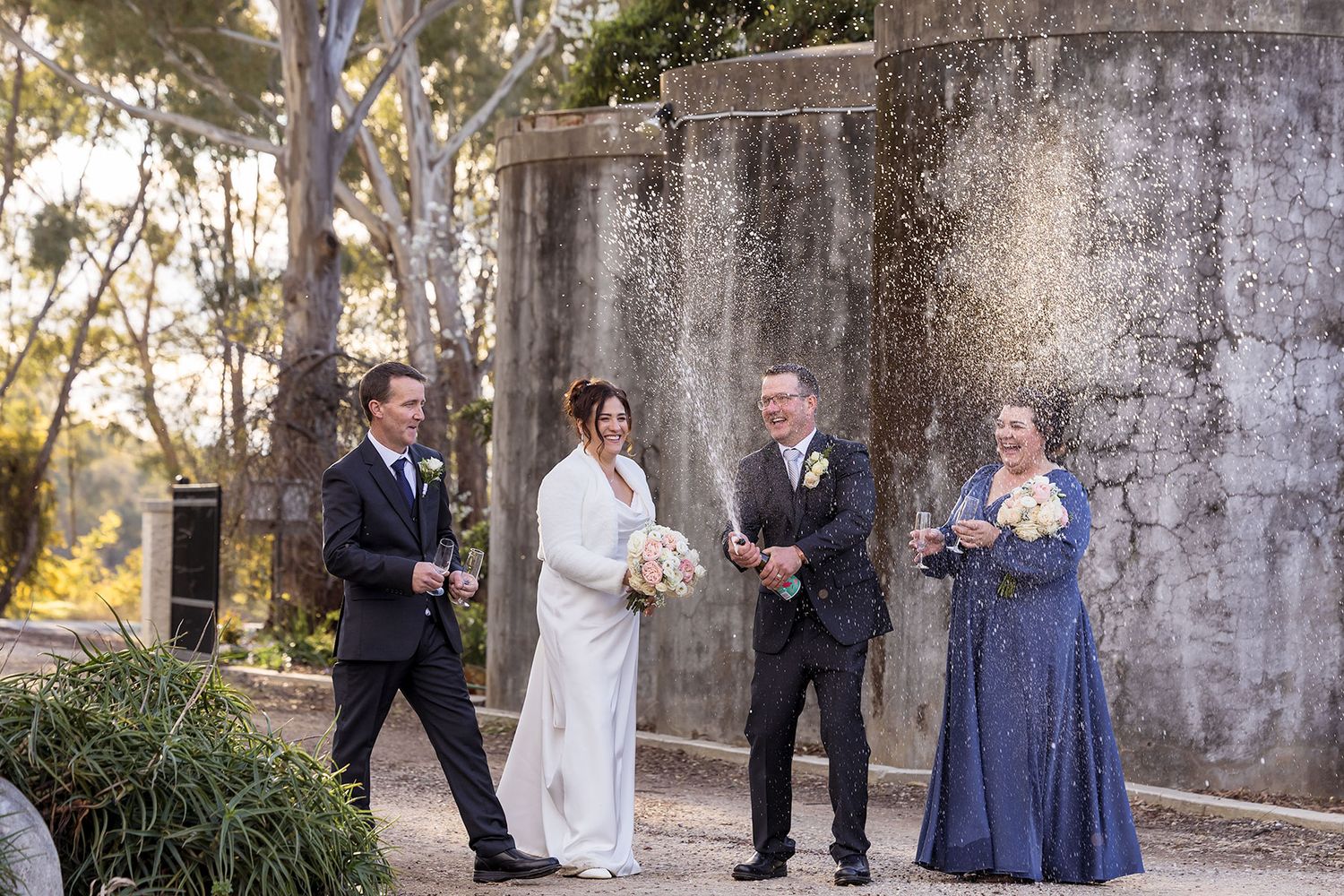 Bride and Groom with their bridal party spray champagne at Buller Wines after their wedding ceremony.