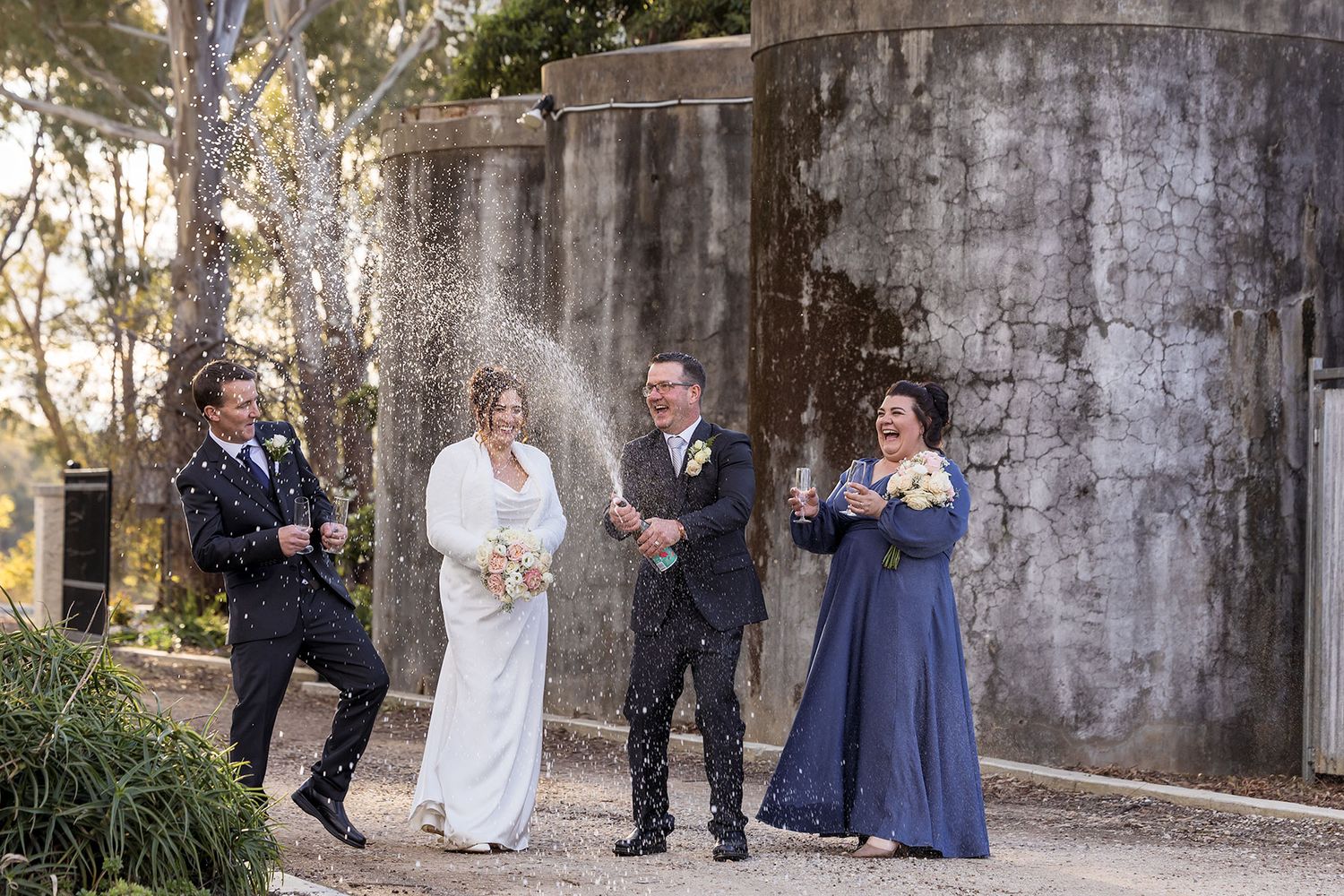 Bride and Groom with their bridal party spray champagne at Buller Wines after their wedding ceremony.