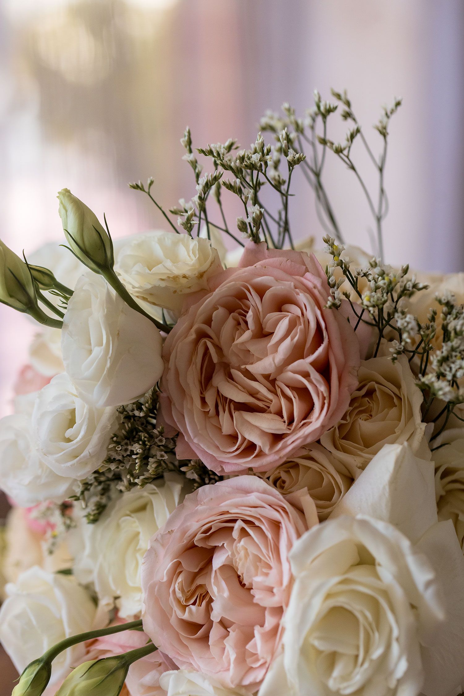 Elegant floral arrangement featuring soft pink garden roses and white roses with delicate greenery in romantic lighting.