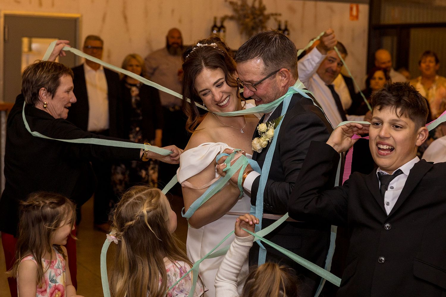 Wedding guests dance and wrap the wedding couple in coloured ribbons during their first dance at the wedding reception at Buller Wines.