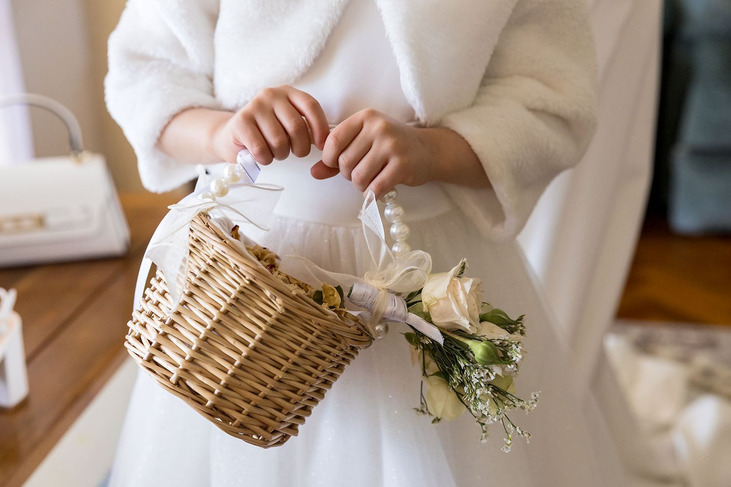 Delicate white flower bouquets being carried in woven wicker baskets at an elegant wedding ceremony.