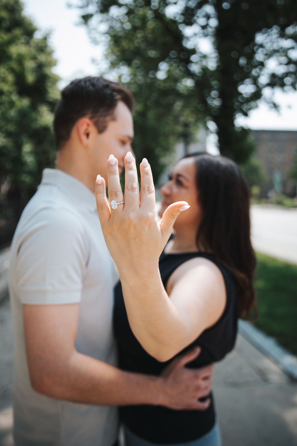 A close-up shot of a hand displaying an engagement ring during an outdoor photo session.