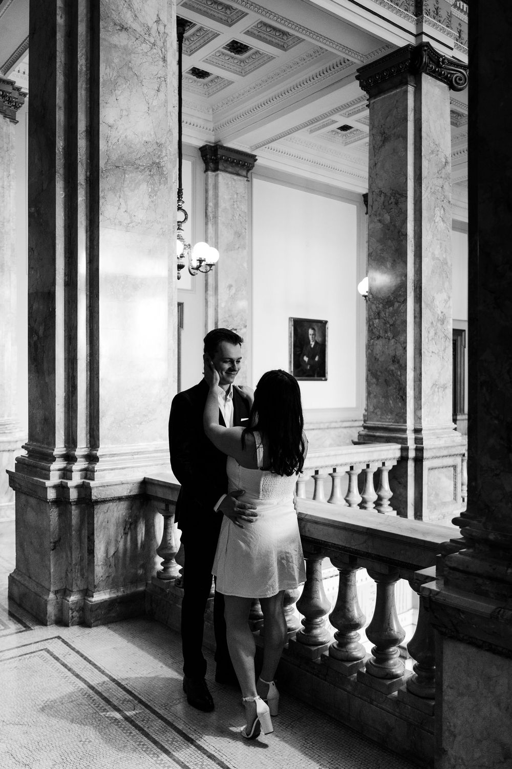 A romantic black and white moment captured in an elegant marble hallway with ornate architectural details.