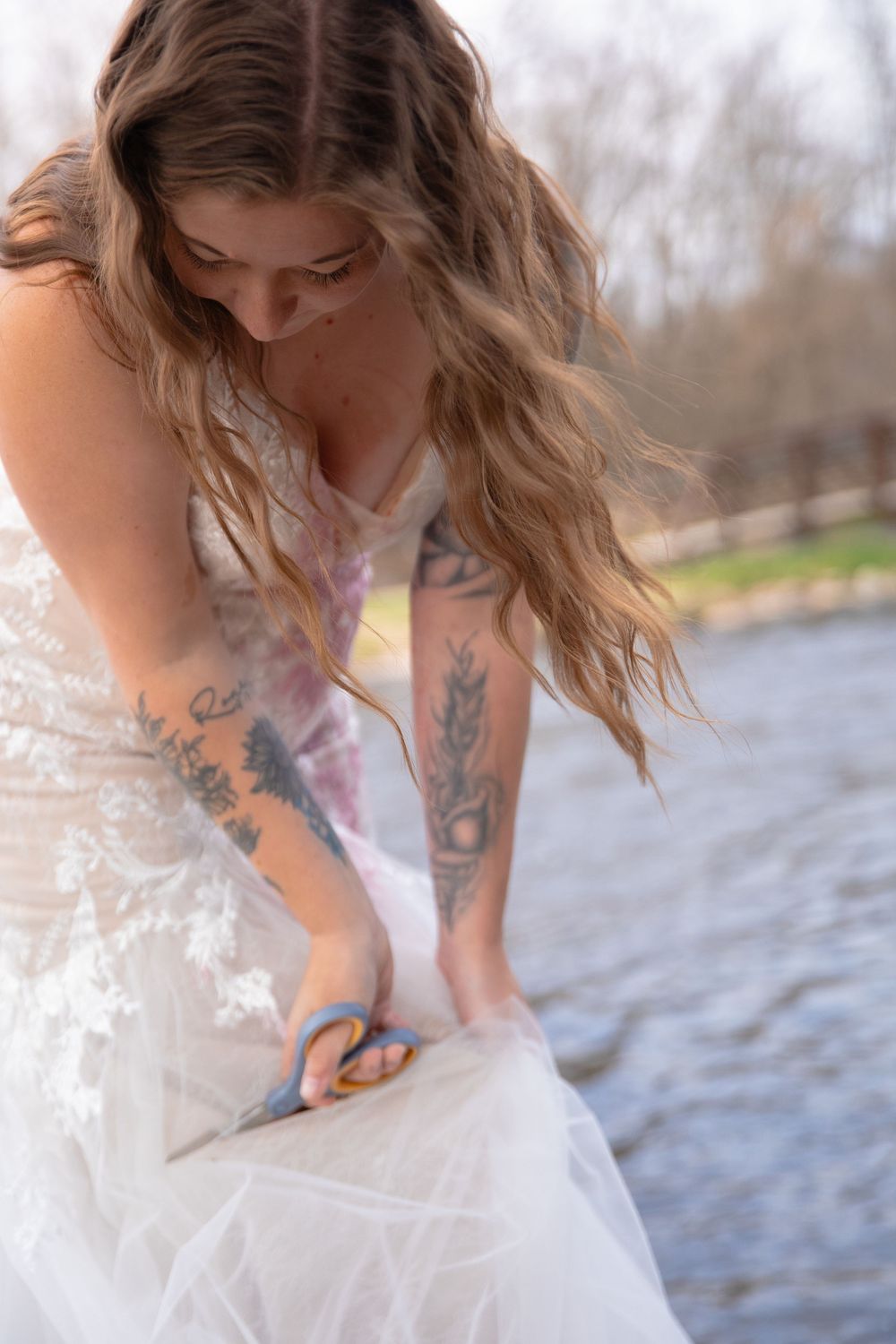 Close-up of woman in white dress with visible tattoos near water.