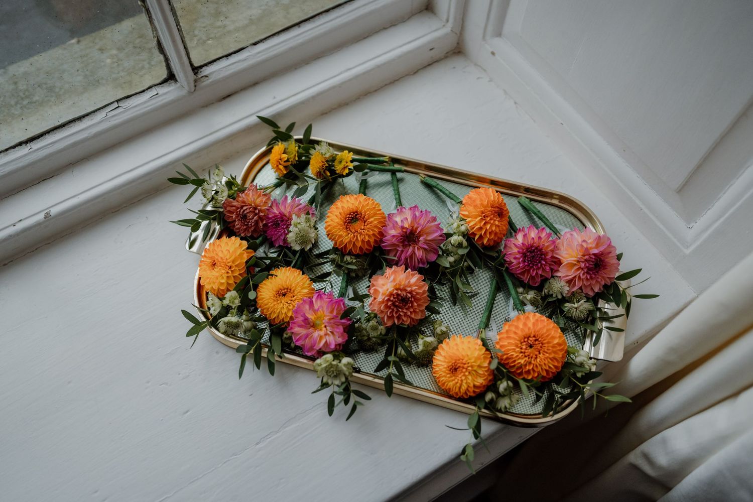 Colorful orange and pink floral arrangements displayed on a windowsill.