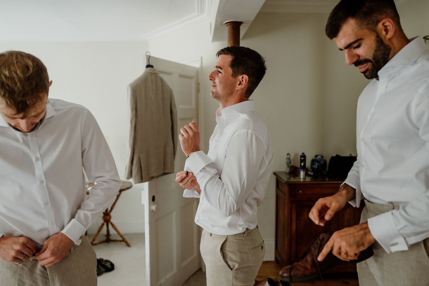 Group getting ready in crisp white shirts before wedding ceremony.
