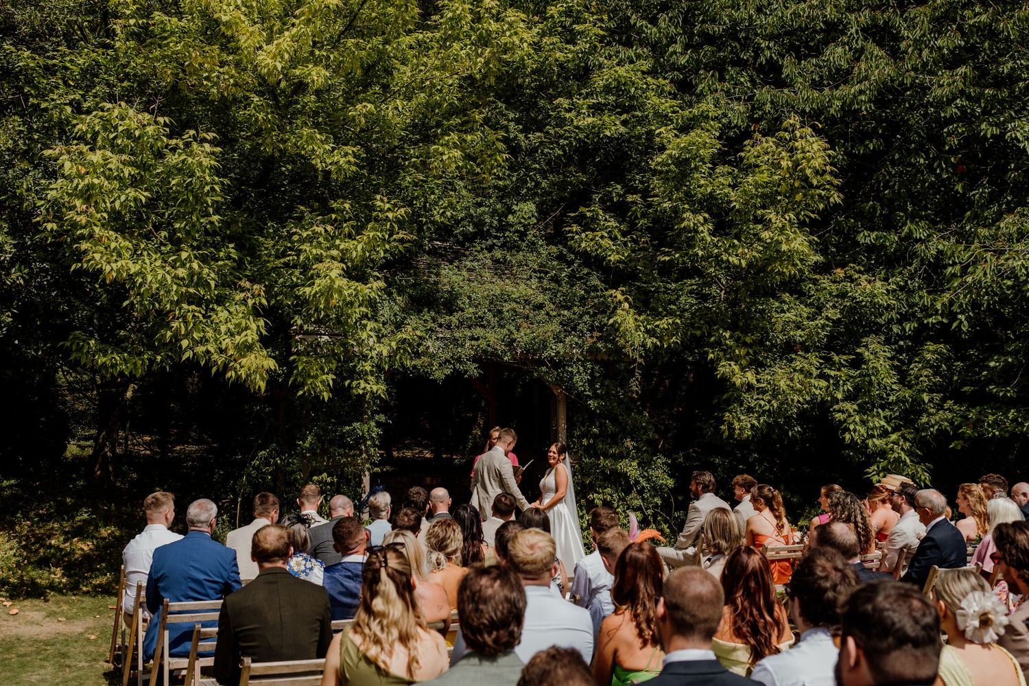 Wedding guests seated in rows for an outdoor garden ceremony.