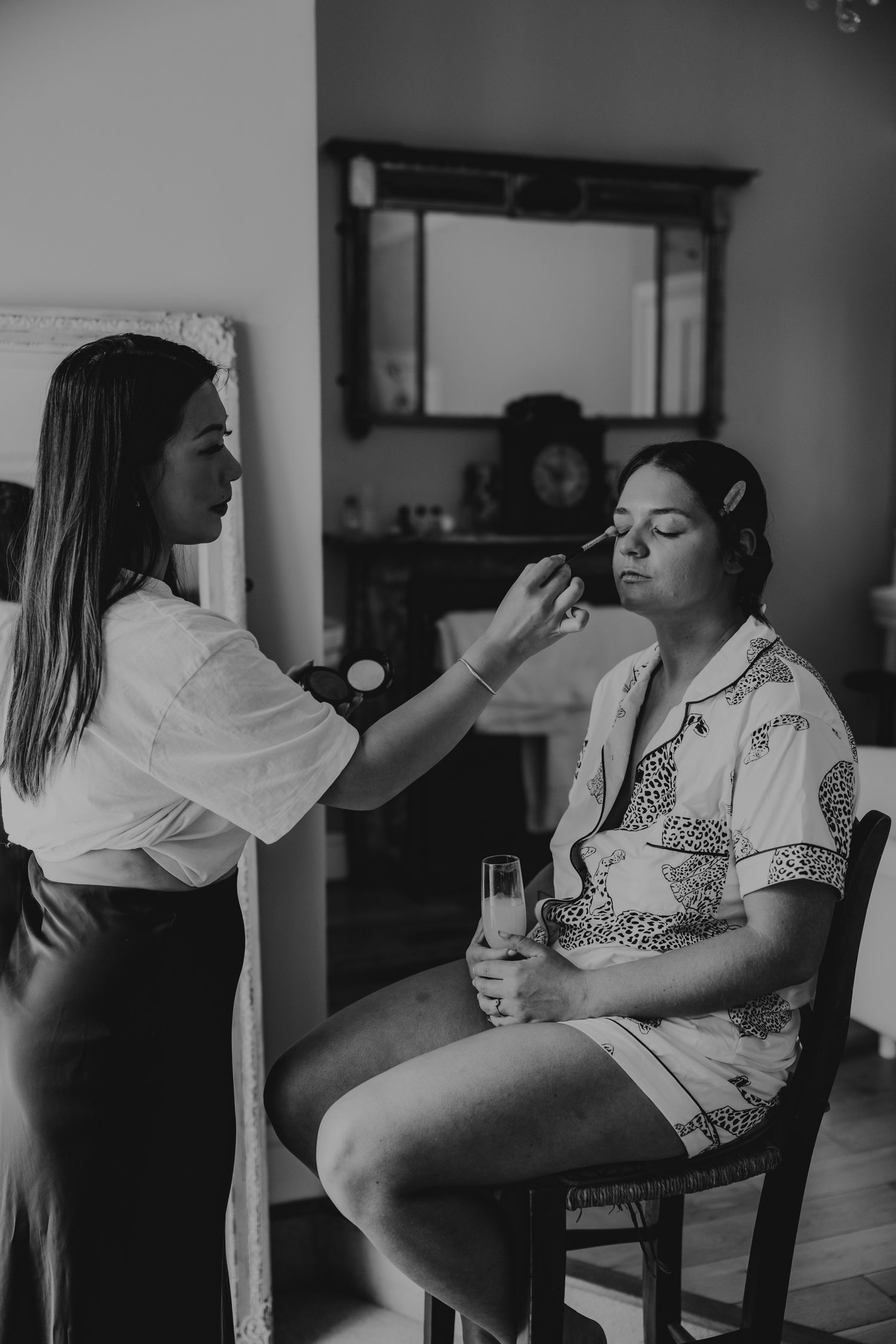 Black and white photo sequence of wedding preparations with makeup being applied.