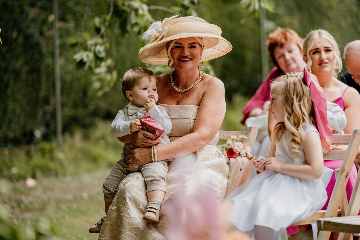 Wedding guests enjoying outdoor party in summer garden with children playing.