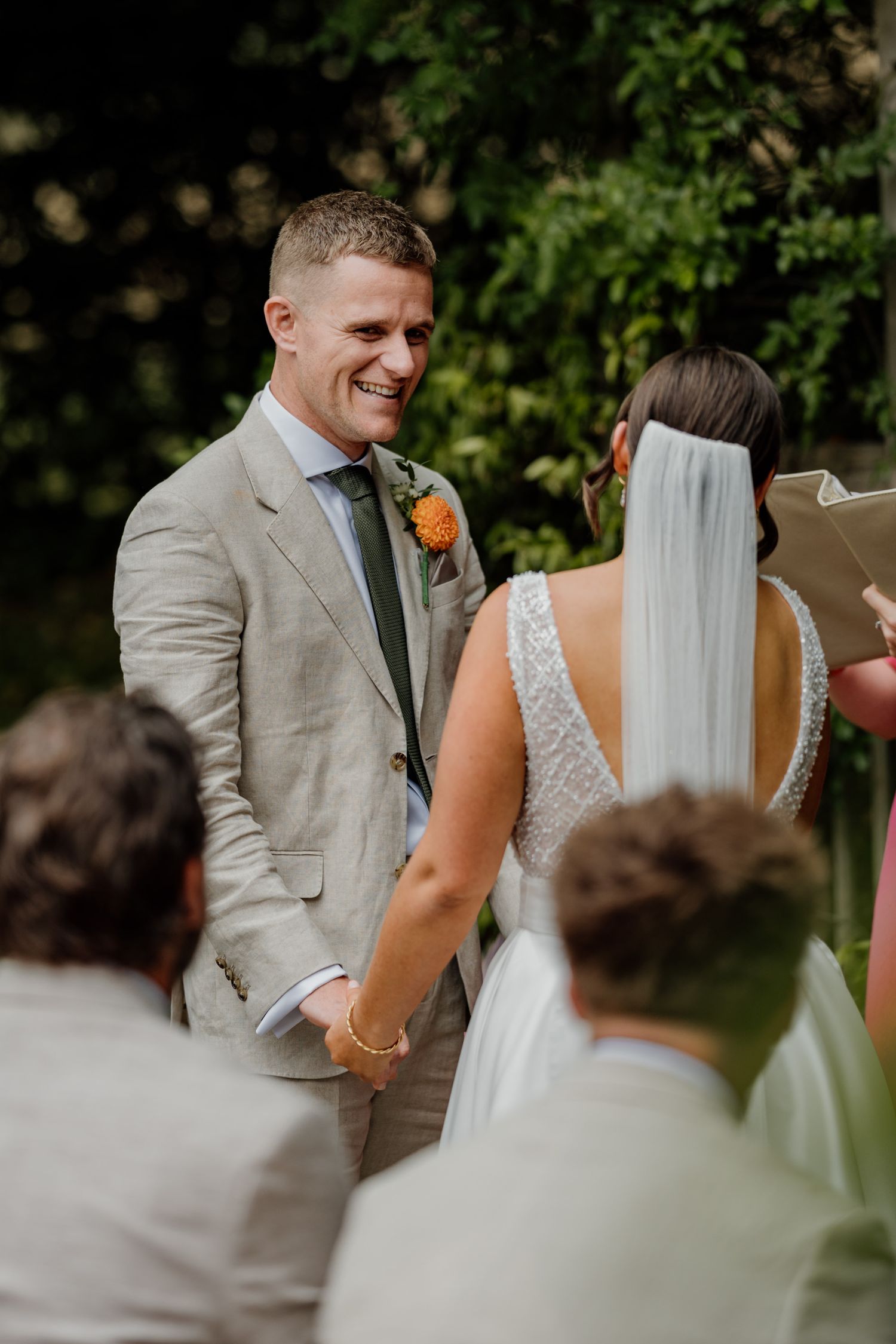 Wedding couple exchanges joyful looks during their outdoor ceremony while guests watch.