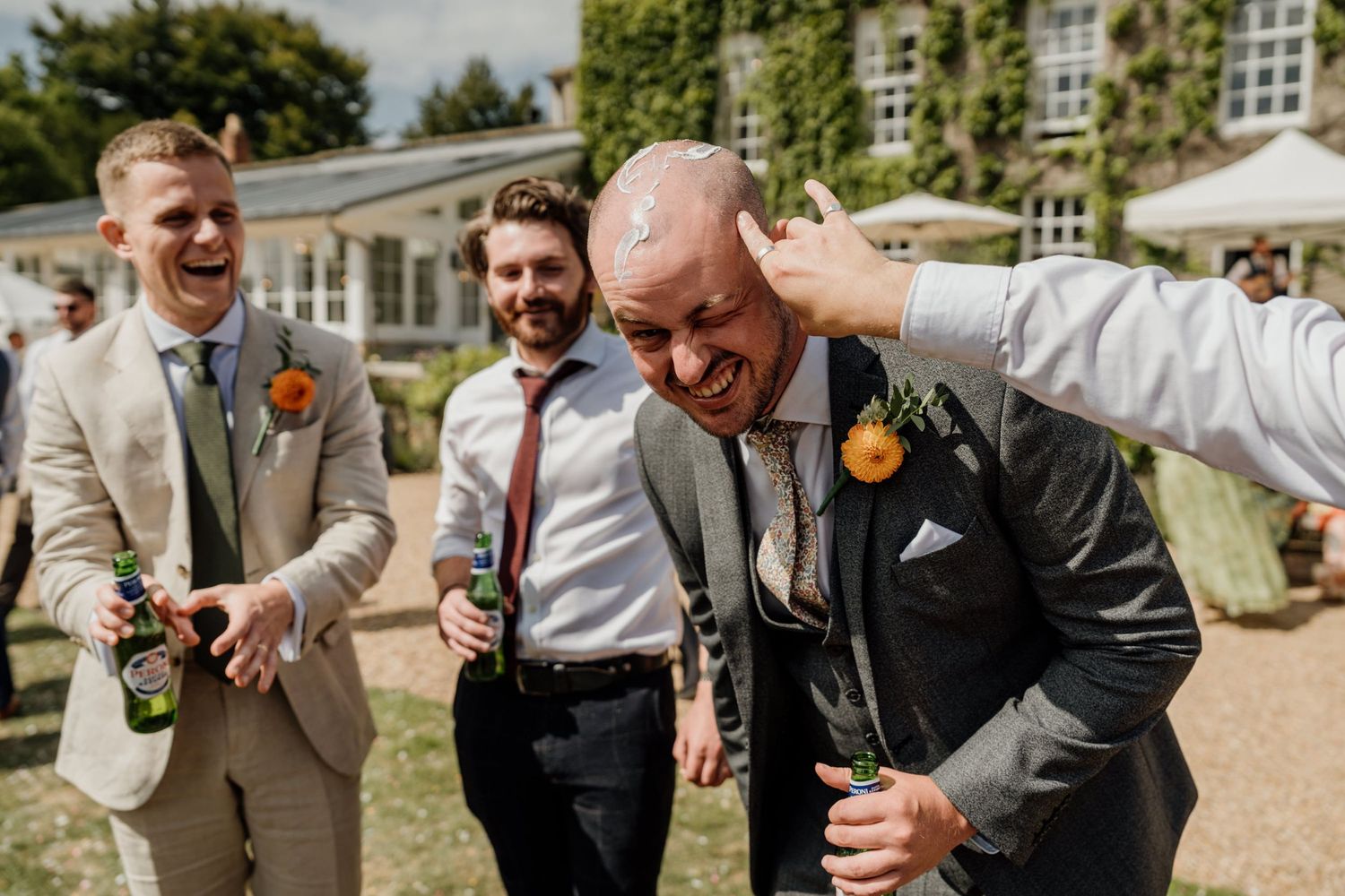 Joyful people in formal attire sharing a candid moment during an outdoor celebration on a sunny day.