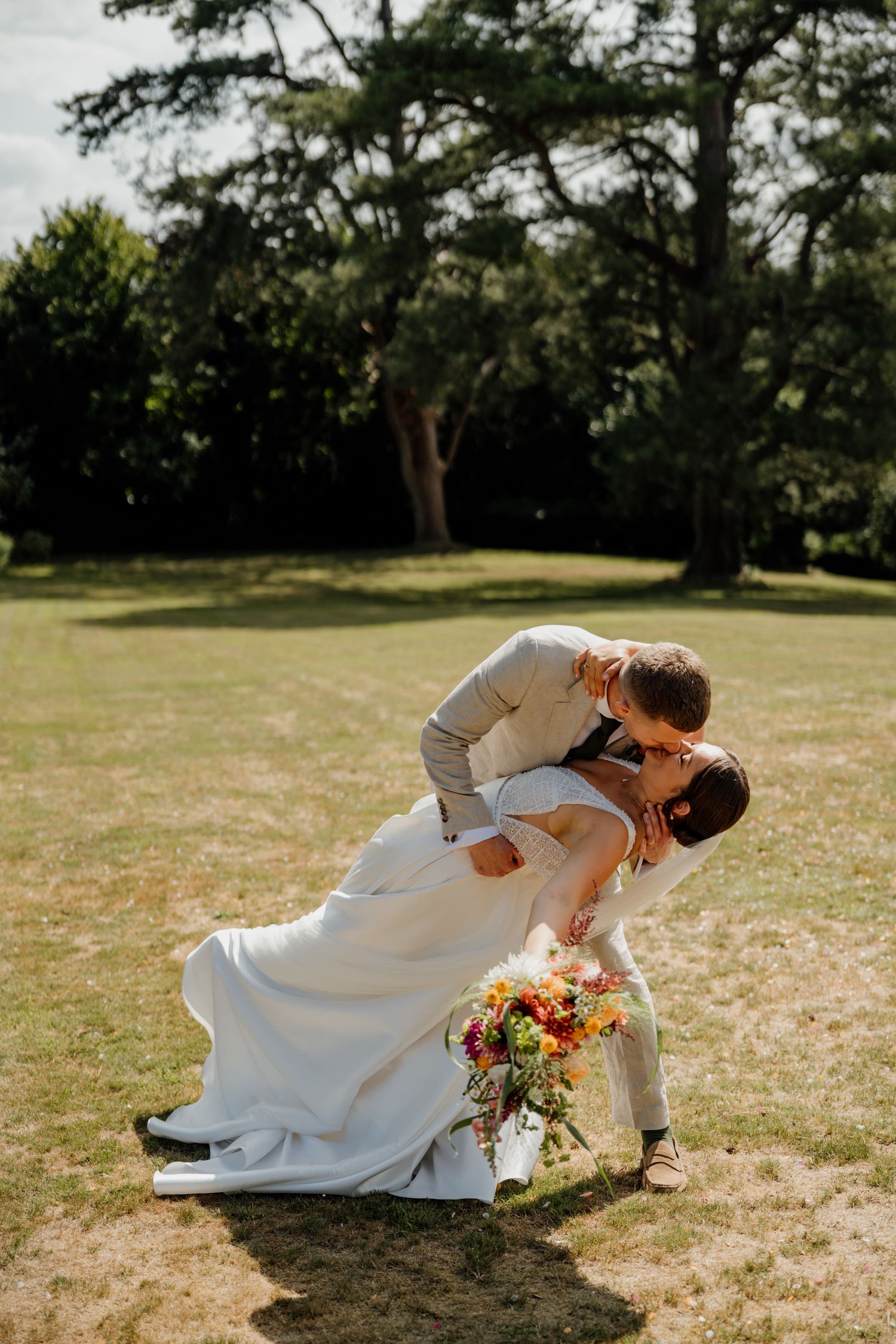 A romantic outdoor wedding photo sequence showing a graceful dip pose on a sunny lawn.