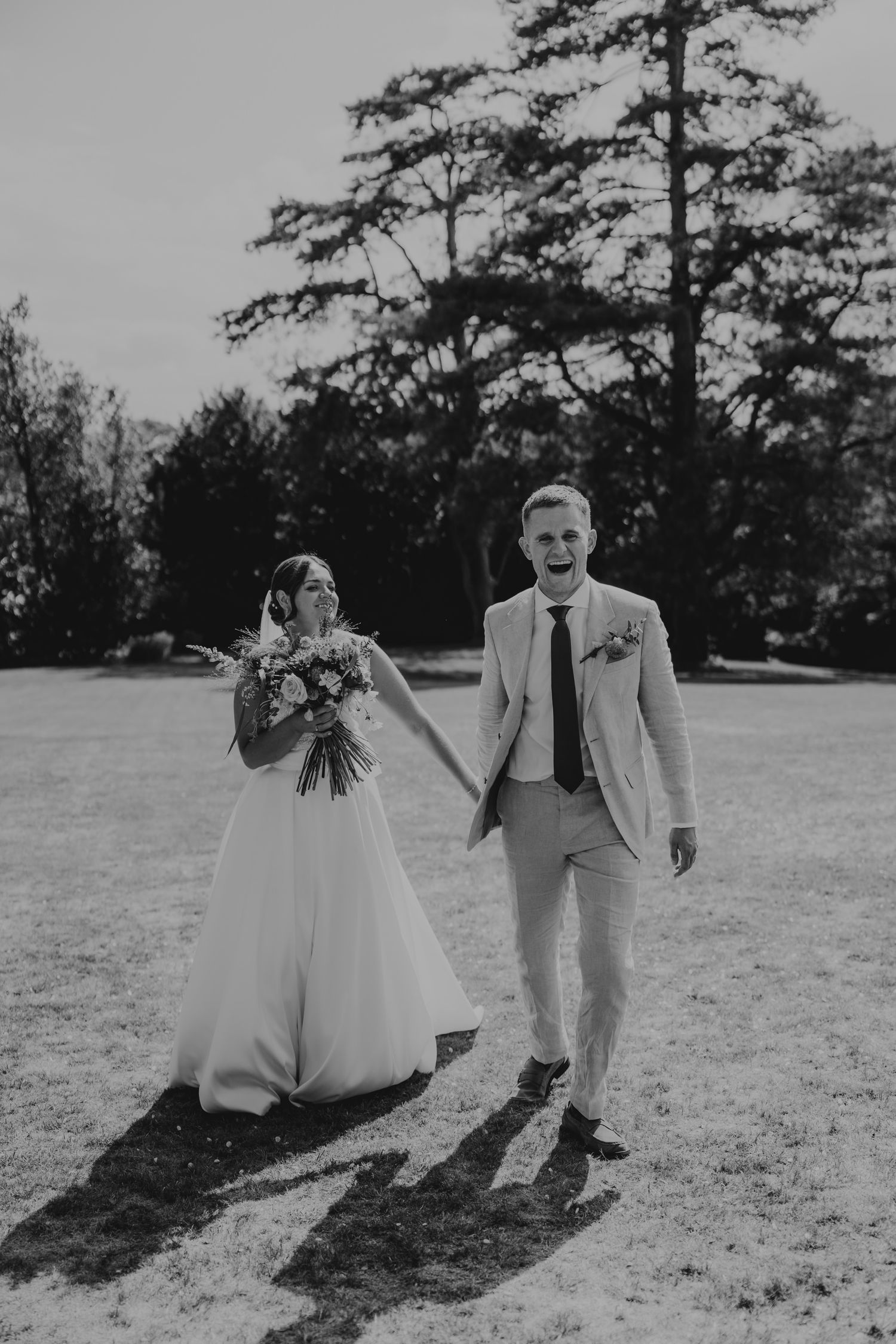 A black and white wedding photo of a couple on their special day, with tall trees in the background.