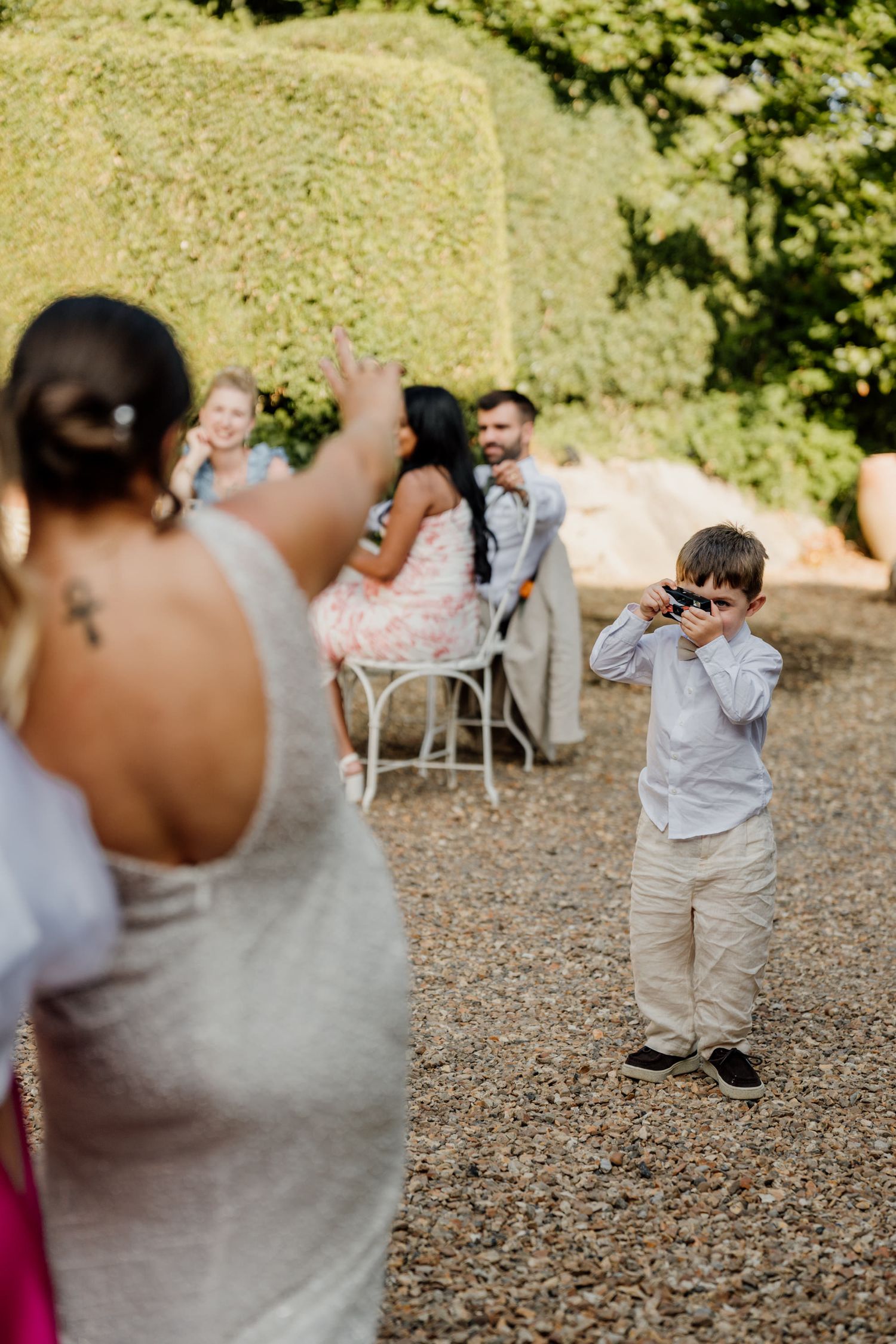 Wedding guests enjoying themselves dancing and celebrating on a gravel courtyard at an outdoor reception.