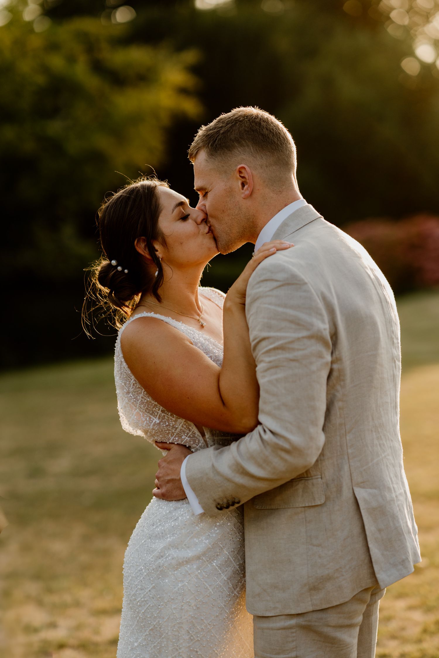 Romantic sunset wedding portraits showing couple kissing in warm golden light.