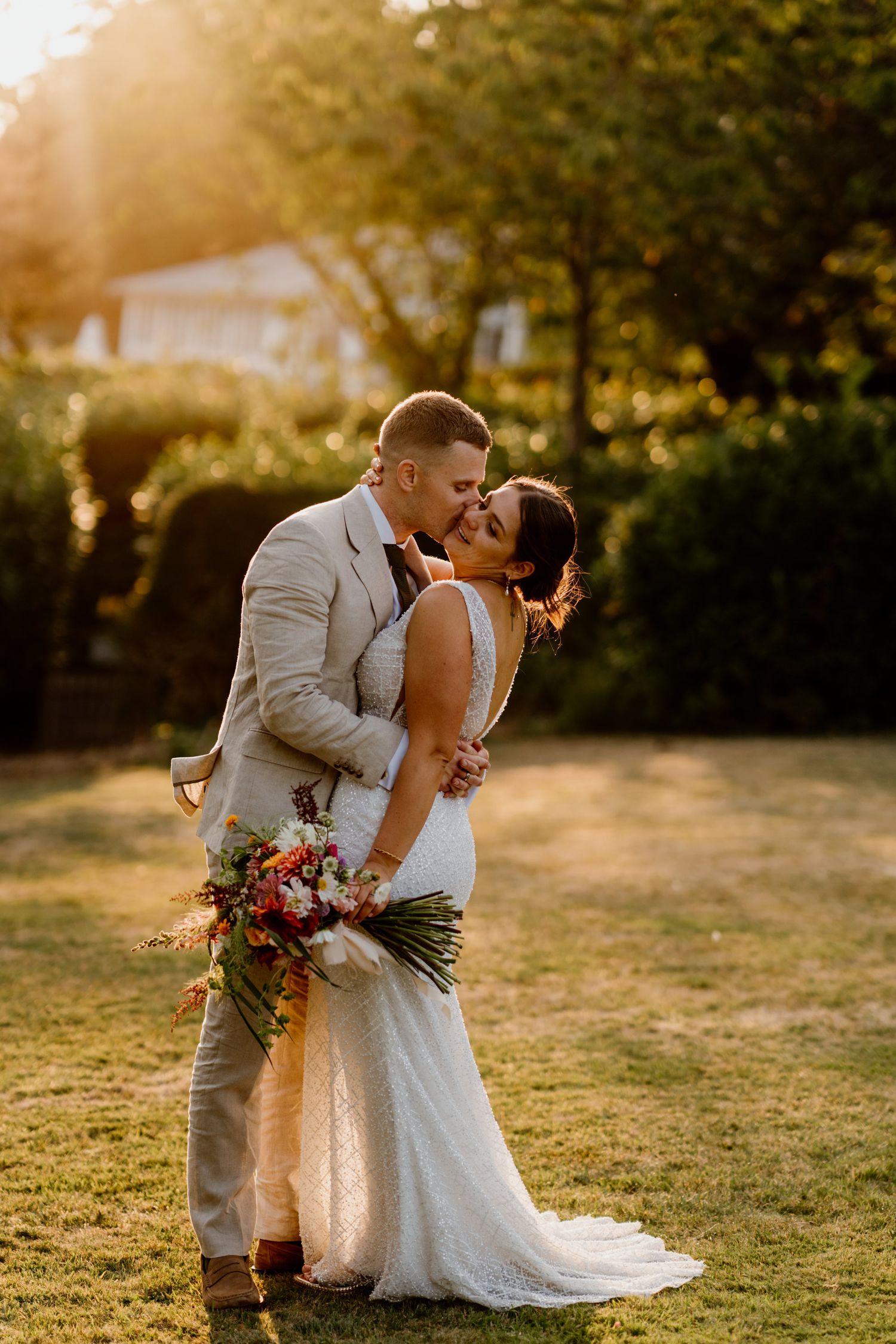 Golden sunset light illuminates a couple sharing a romantic moment during their outdoor wedding photoshoot.