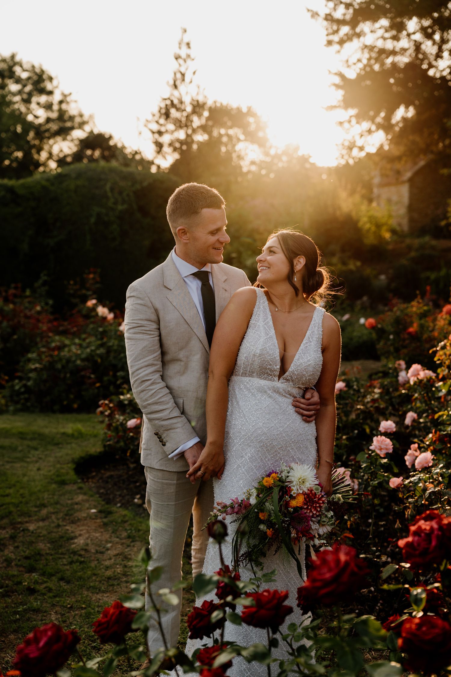 A romantic sunset photo session in a rose garden with pink and red flowers blooming.
