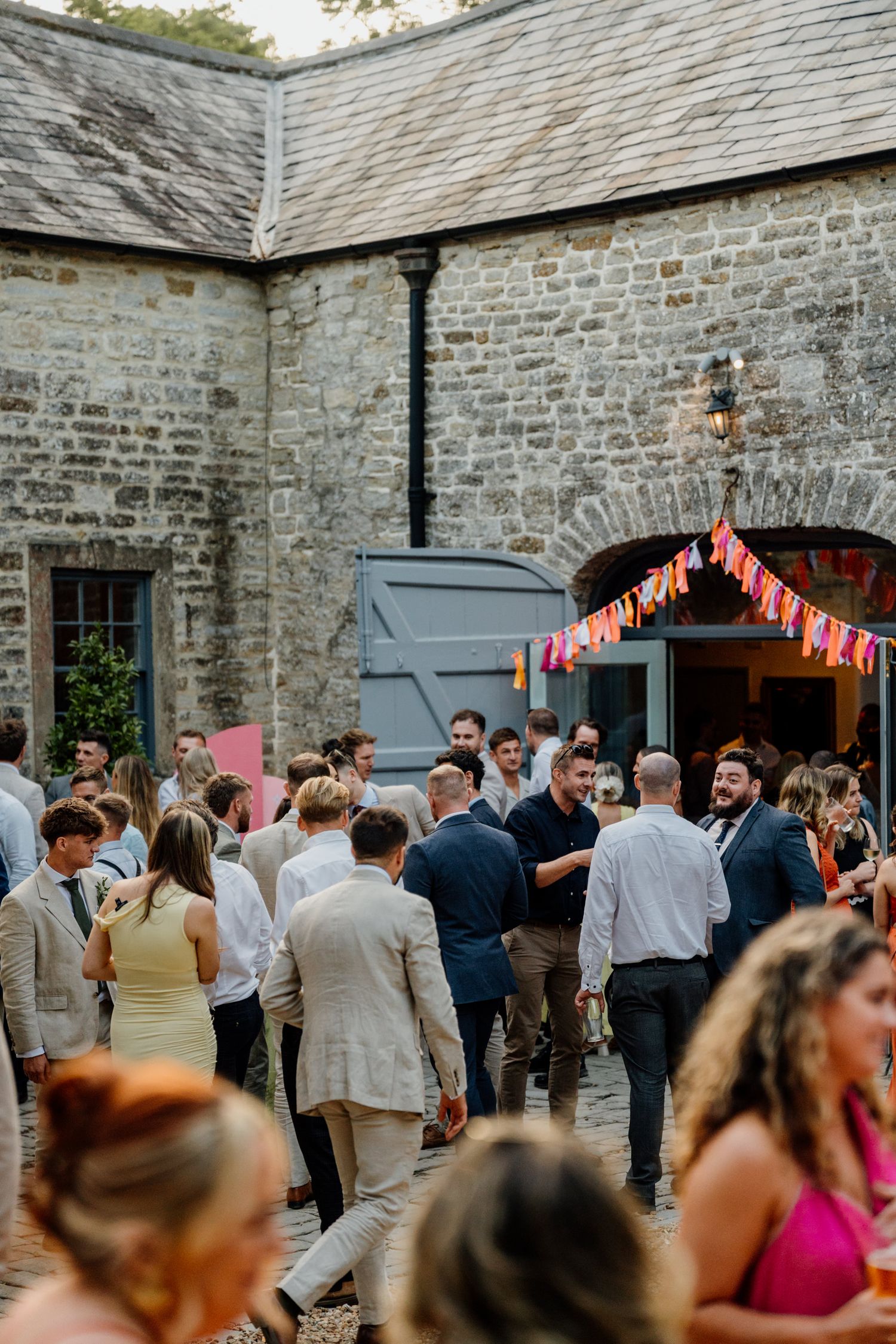 Wedding reception party at a rustic stone barn venue with string lights and guests dancing.