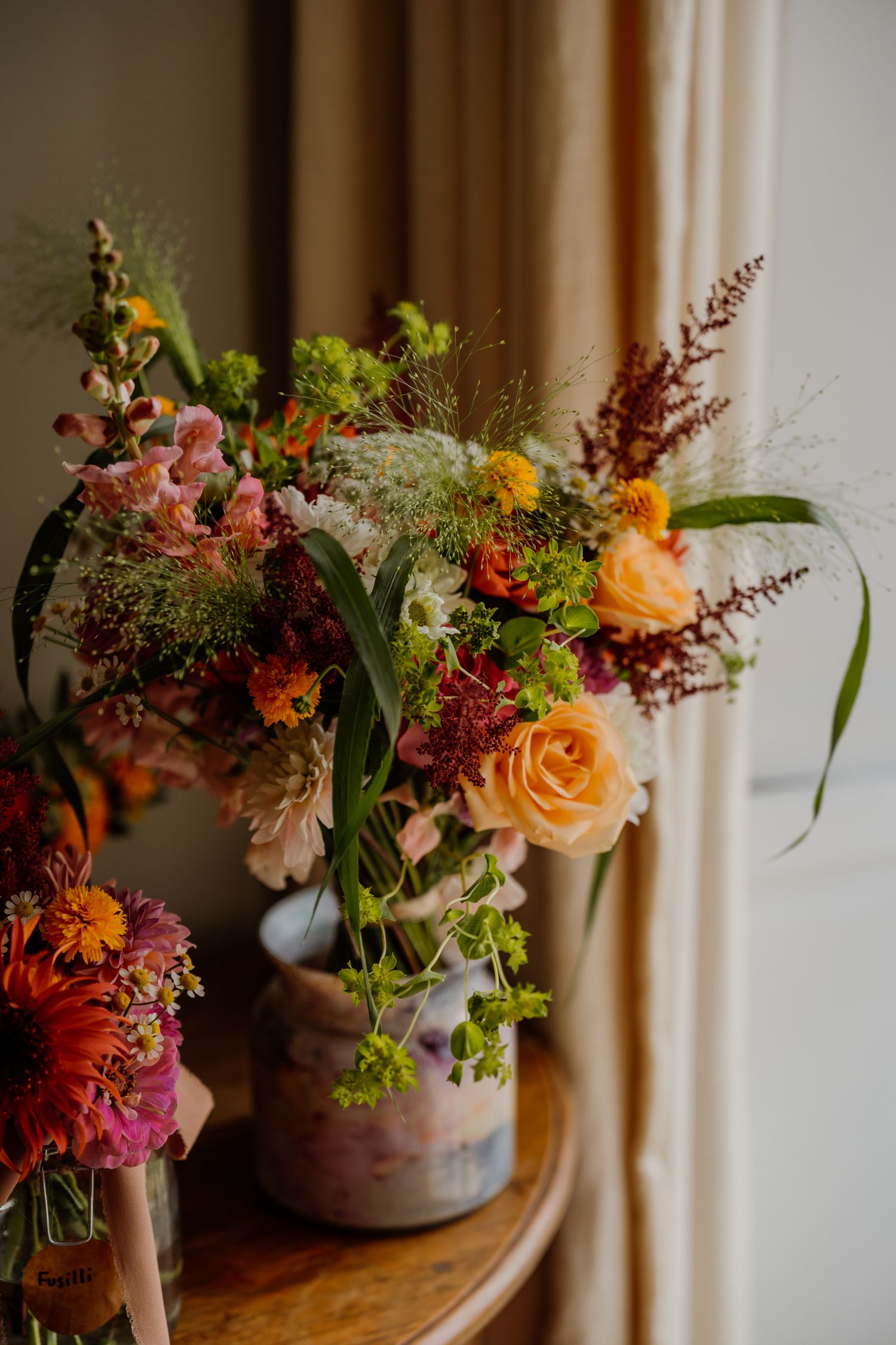 Vibrant autumn-colored floral arrangements featuring orange roses and pink blooms in vintage containers.
