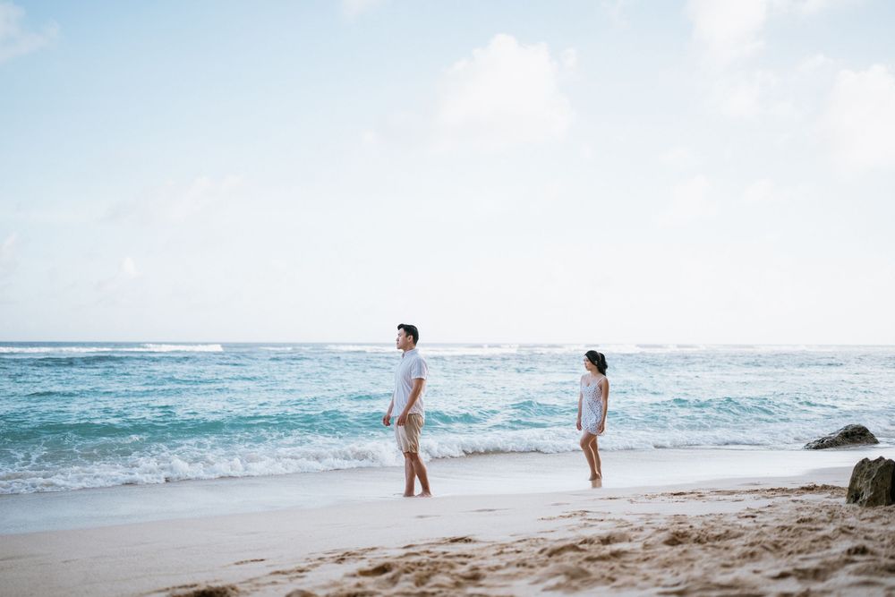 Dreamy beach photography session with couple walking along shoreline at sunset.