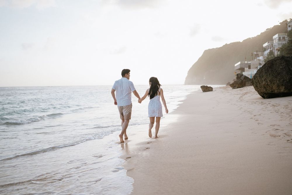 Couple strolling together on pristine white sand beach with ocean views.