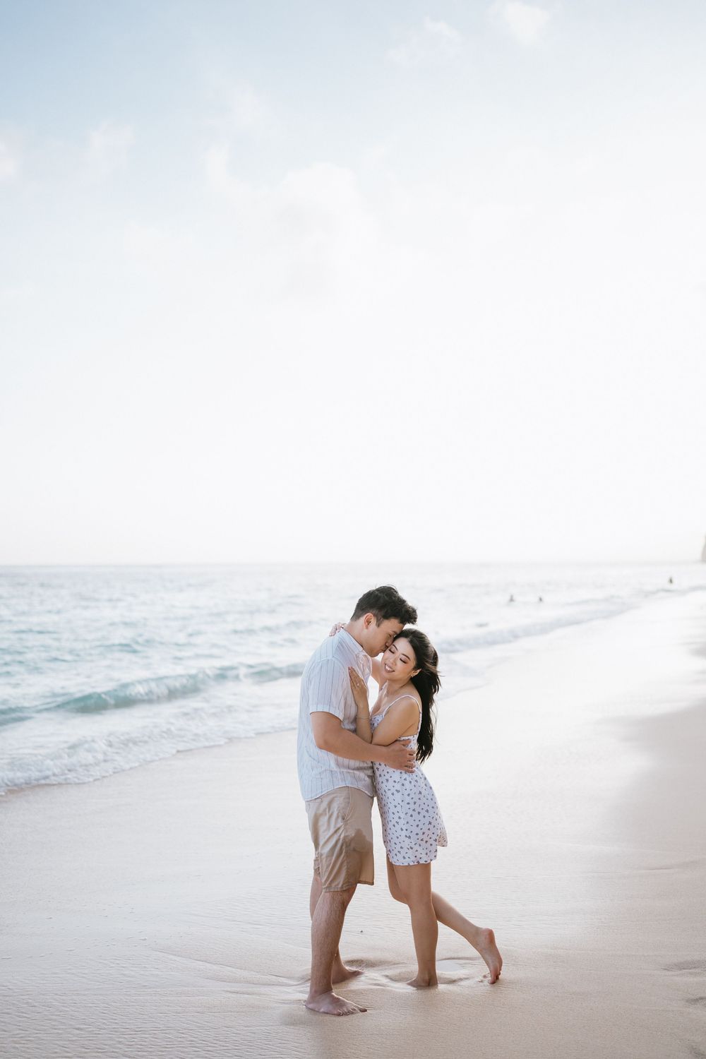Sweet couple's moment captured on sandy beach with soft lighting.