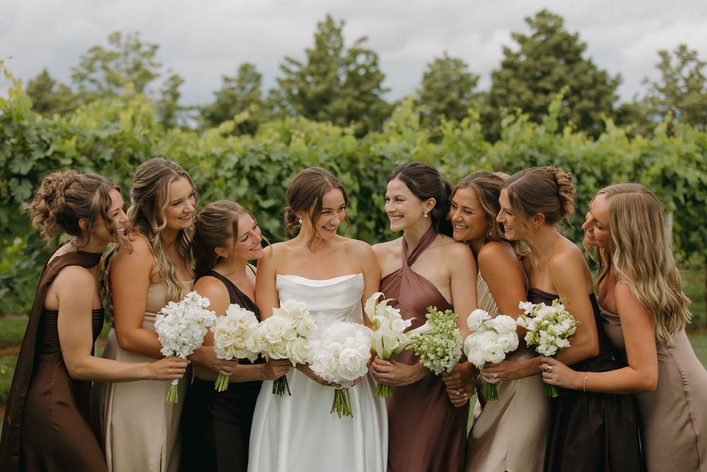 Wedding party members share joyful moments and laughter together in an outdoor setting.