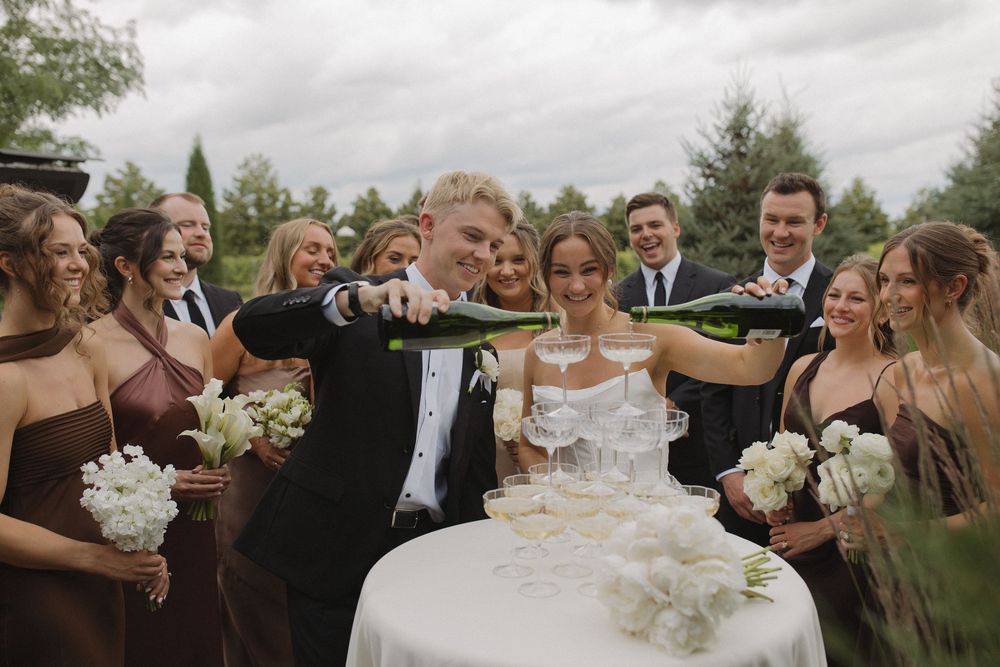 Wedding party celebrates with champagne during outdoor photo session.