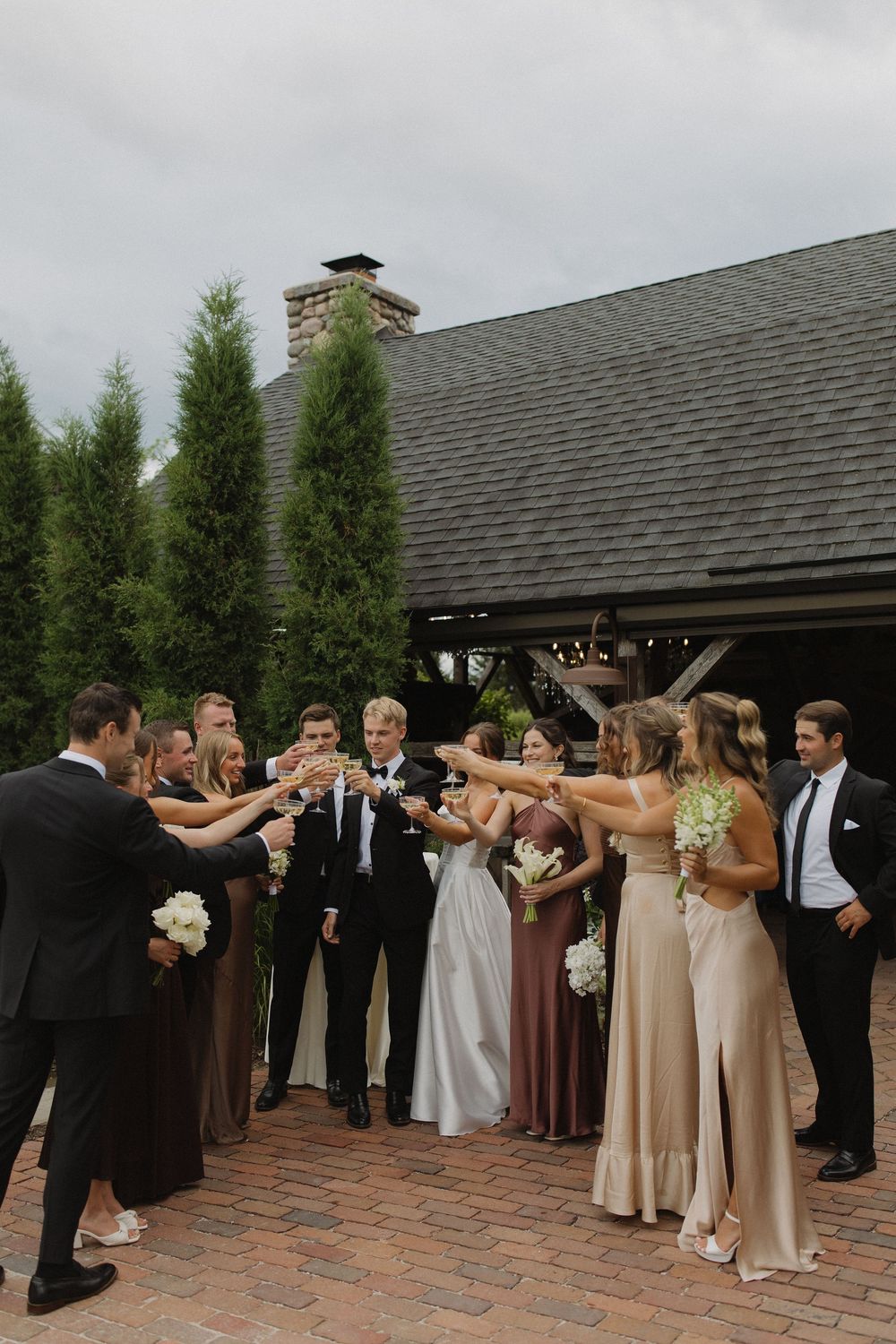 Wedding party performs synchronized dance moves on brick patio during reception.