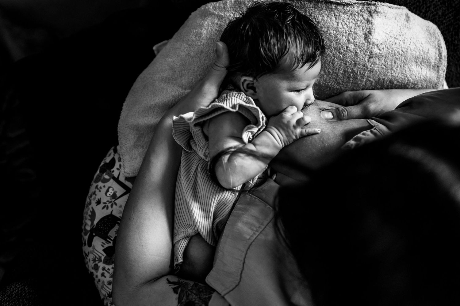 Mom breastfeeding baby during in-home newborn lifestyle session in New Orleans.