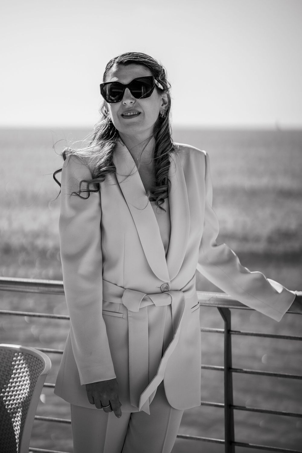 Person in an elegant white blazer poses against a minimalist background in black and white photography.