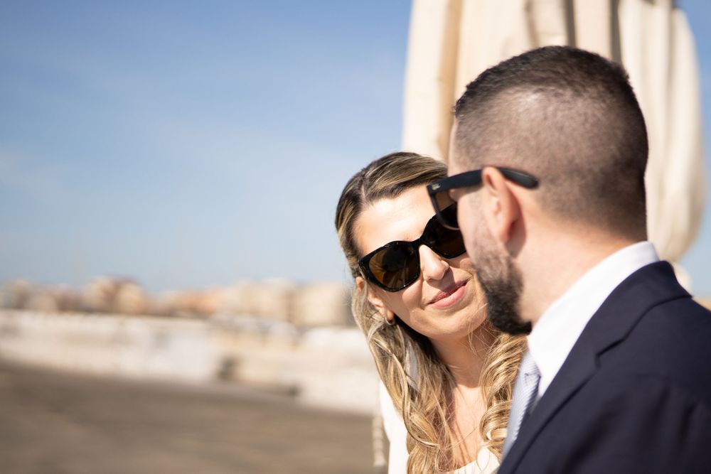 Two people pose together in multiple scenic shots while one wears a wedding dress and the other wears a formal suit.