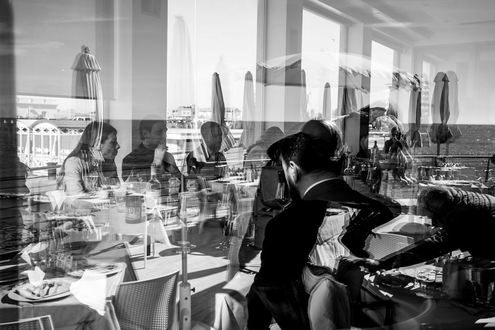 Black and white panoramic view of a modern interior space with city buildings visible through large windows.