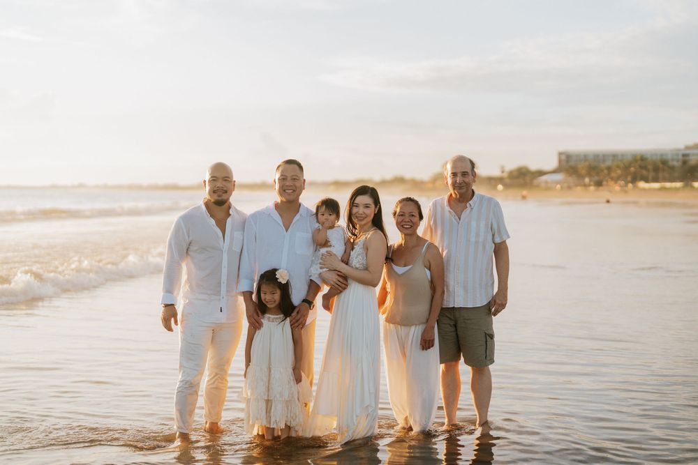 Family group photo on beach wearing coordinated white and neutral clothing at sunset.