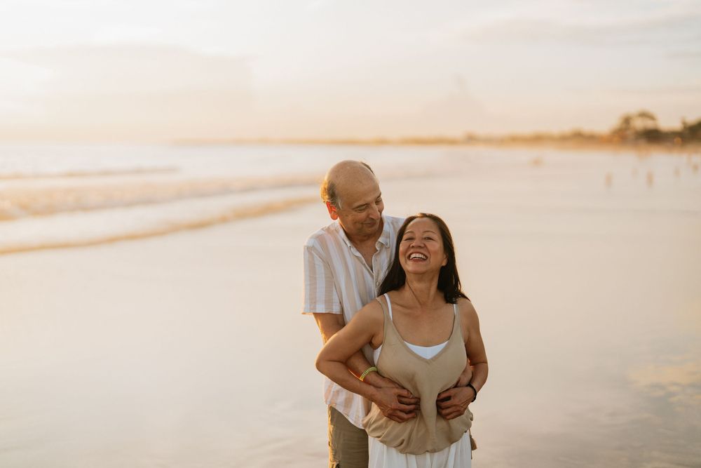 A couple shares a joyful moment together during sunset on a beautiful beach.