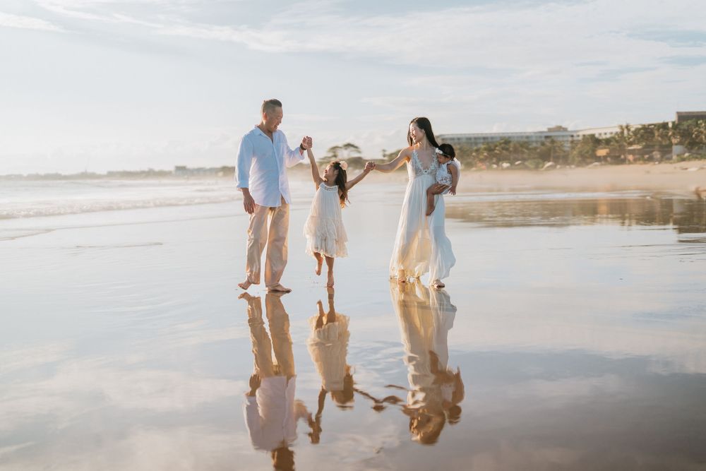 Family enjoying a beach walk together during golden hour.