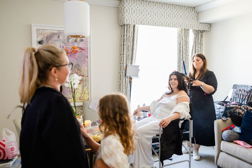 A group of people gather in a bright hospital room during a care session with medical professionals.