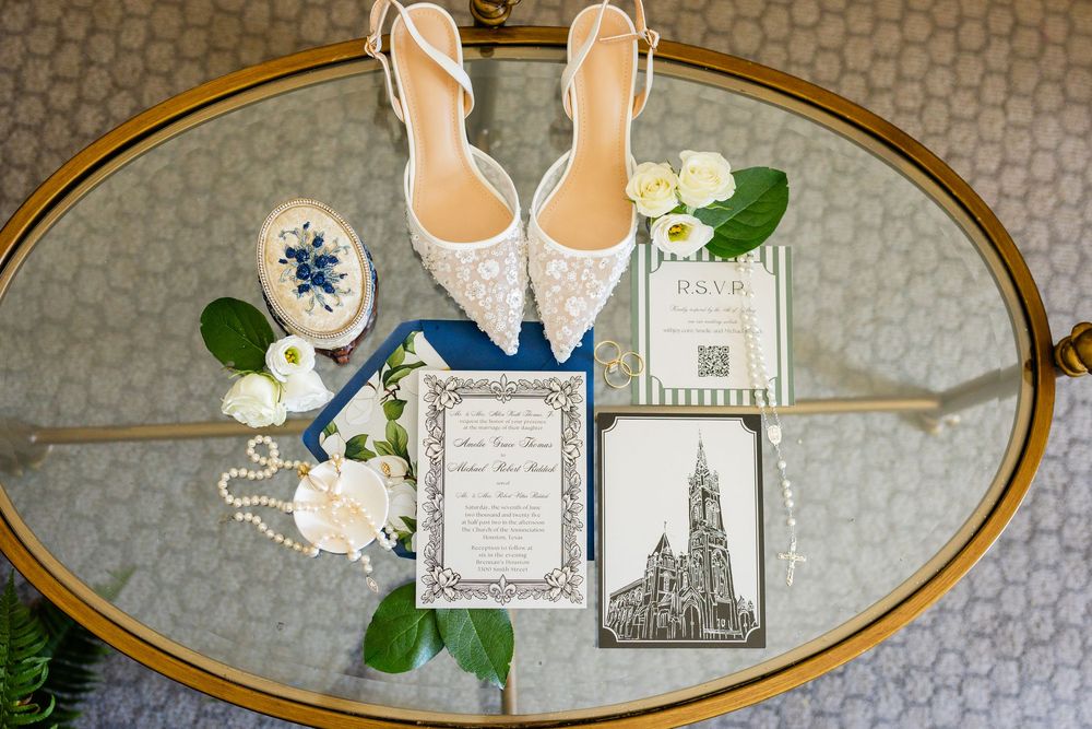 Wedding details flatlay showing invitation, rings, bridal shoes and floral elements arranged with vintage gold frames.