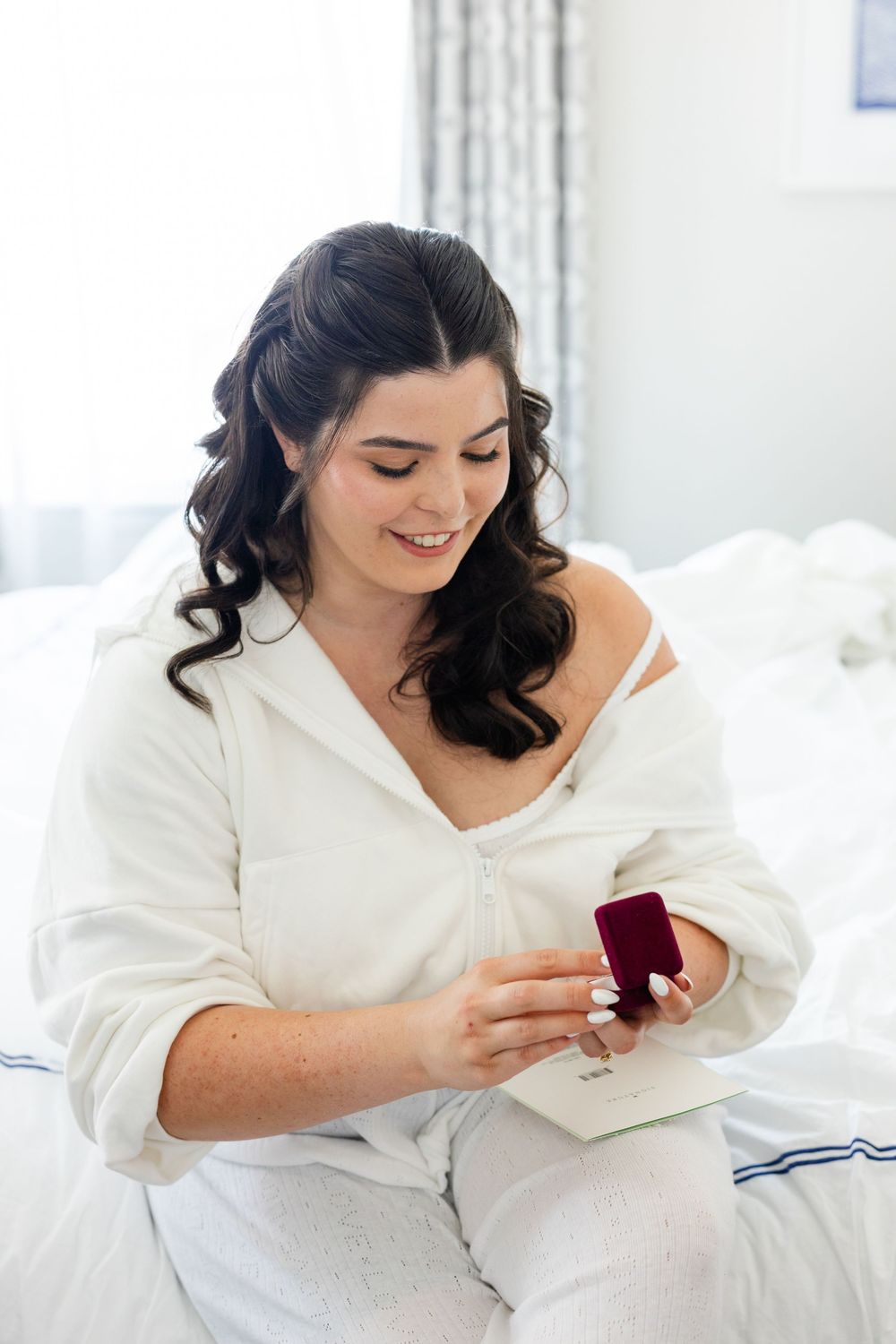 A series of photos showing someone in white opening a small red ring box on a bed.