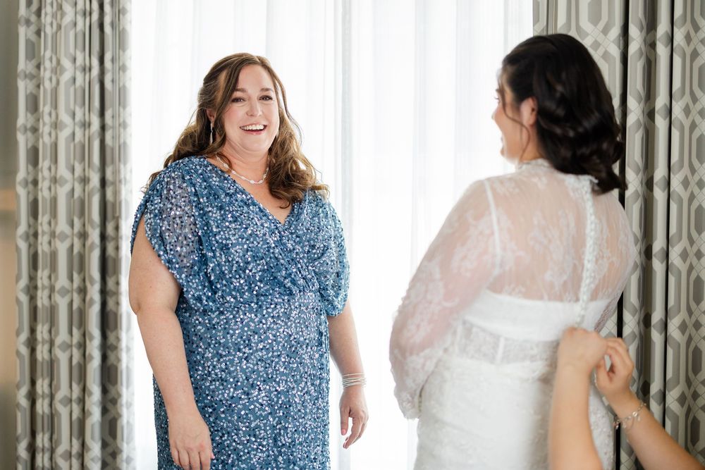 A wedding party wearing blue and white dresses poses together in an elegant setting.