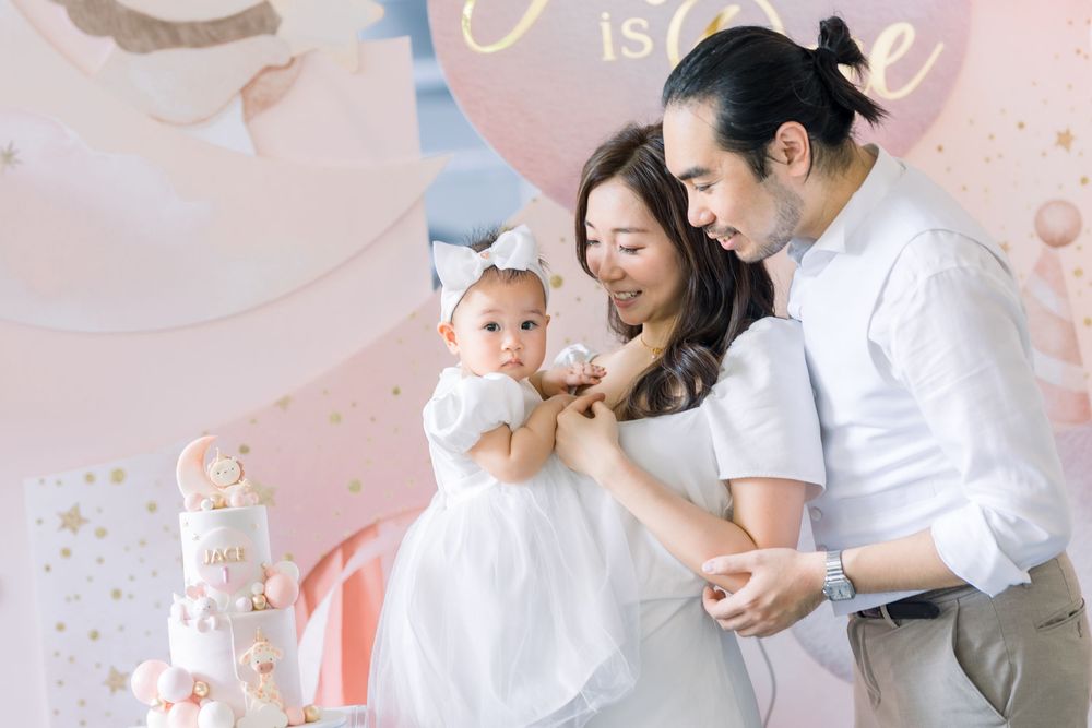 Six connected photos show tender family moments during a baby's first birthday cake smash photoshoot on pink backdrop.