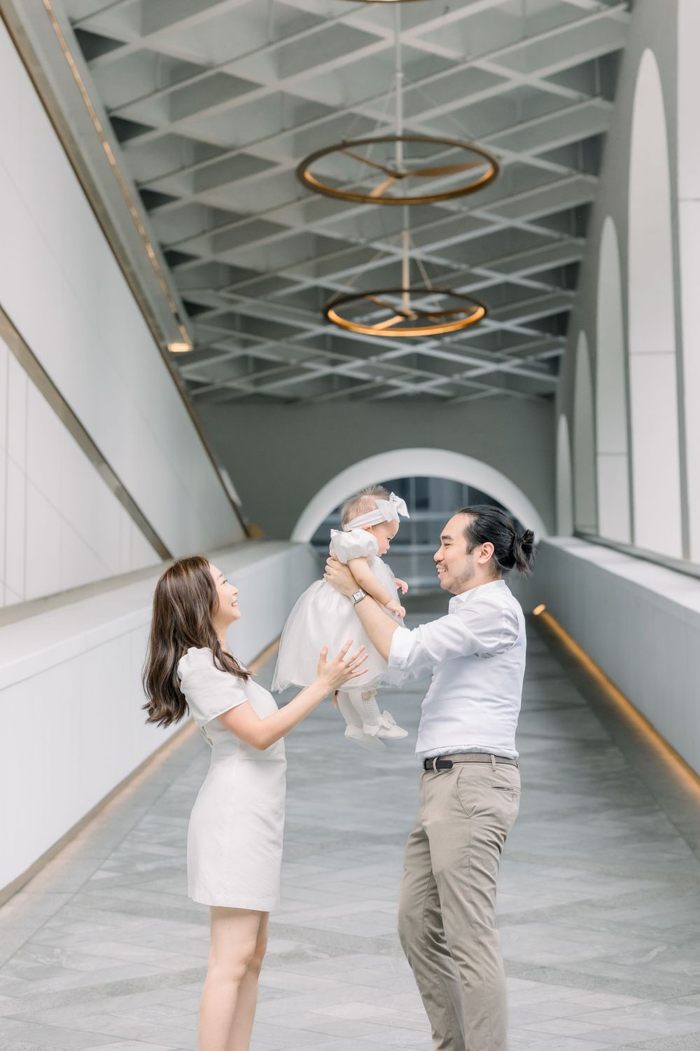 Four sequential photos show a couple playfully dancing and twirling in a modern hallway with white walls and industrial ceiling.