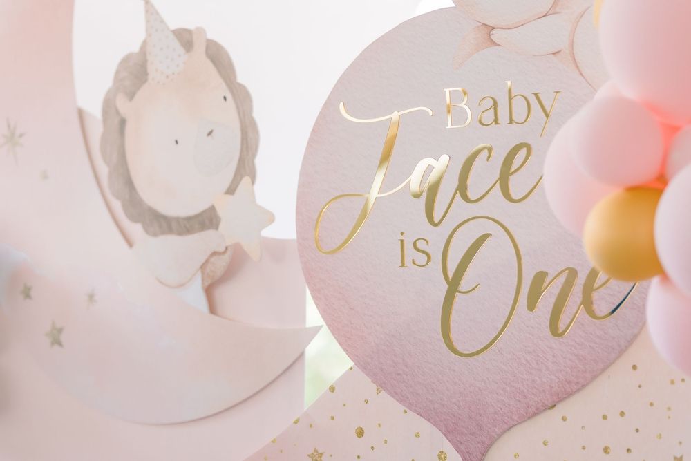 Soft pink and gold baby shower balloons featuring 'Baby' text arranged in an elegant display.