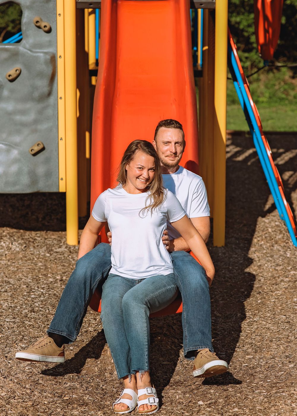 Playful couple sitting together on colorful playground equipment.