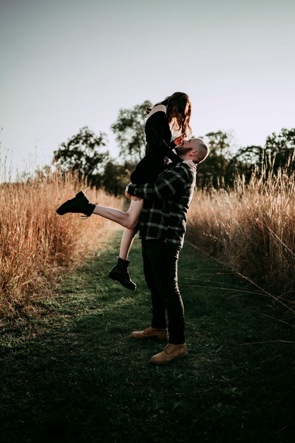 Playful couple poses in silhouette against golden sunset light.