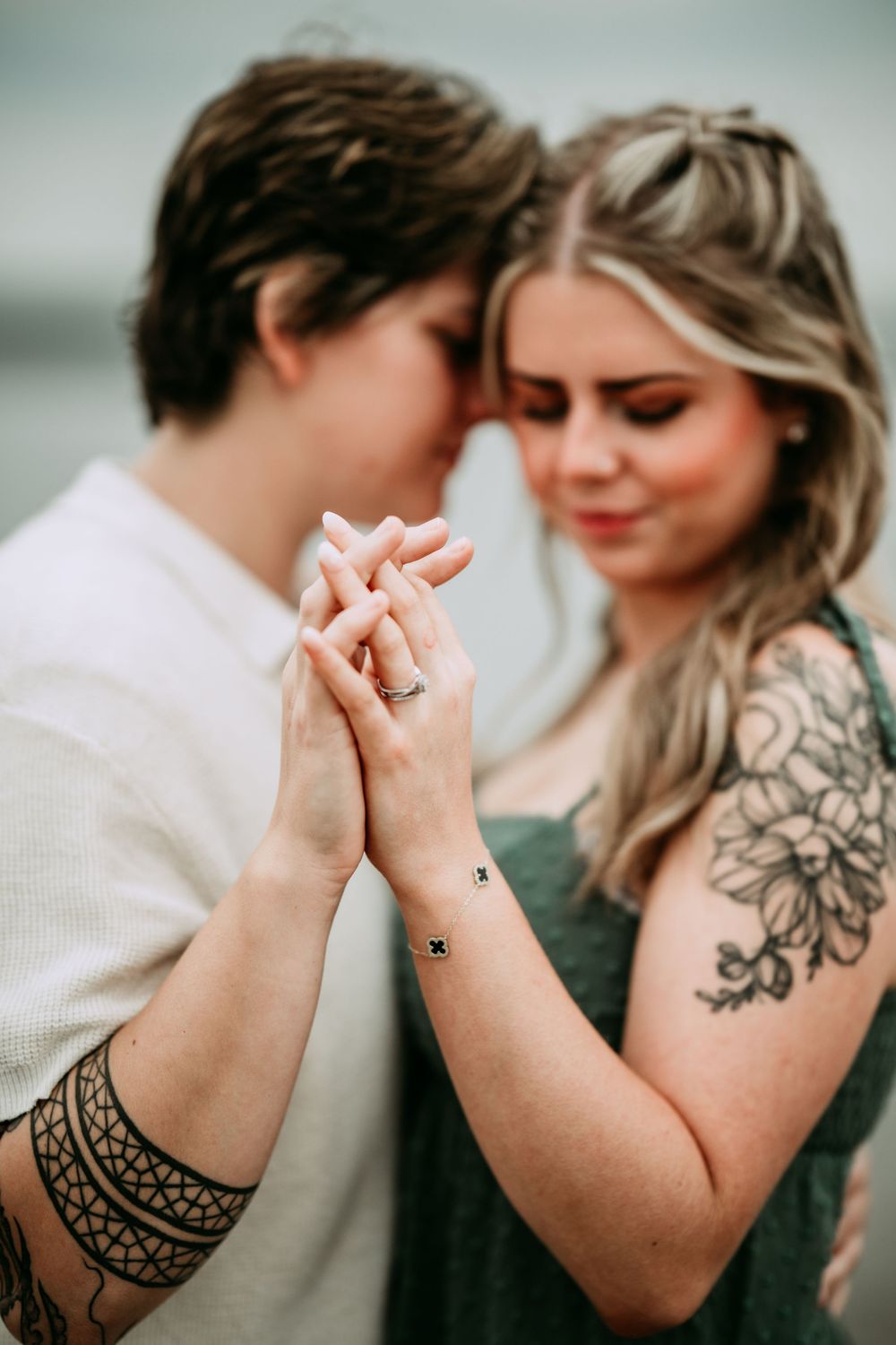 Close-up images of tattooed arms and intertwined hands showing engagement ring.