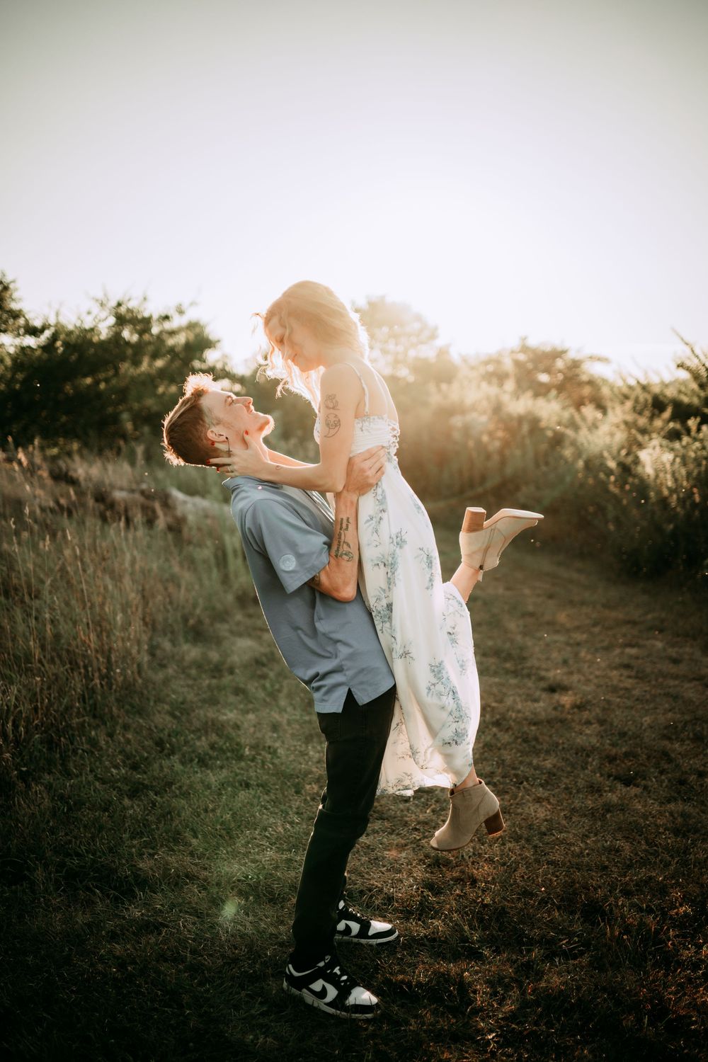 Playful couple dancing and embracing on a hilltop at sunset.